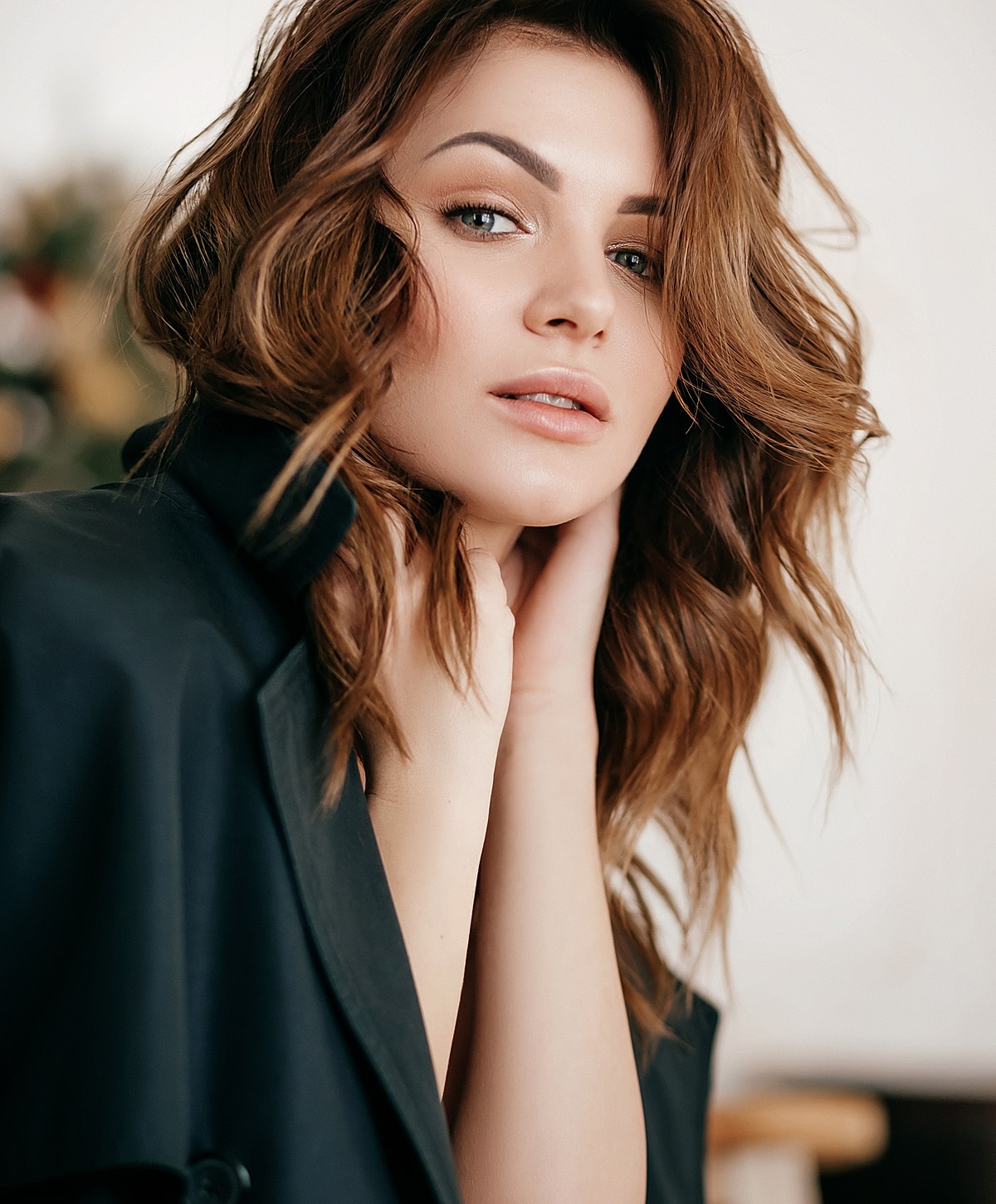 Woman with wavy hair posing softly indoors.