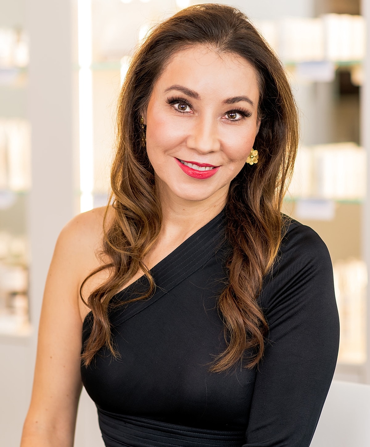 Smiling woman in black suit, skincare background.