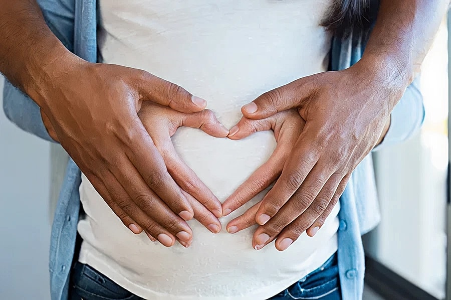 Hands forming a heart on a pregnant belly.