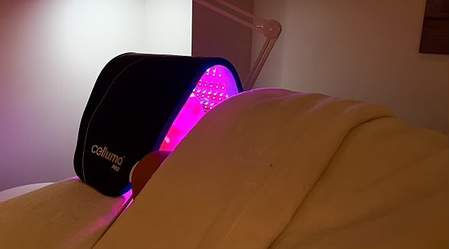 Person using LED light therapy device for skin.