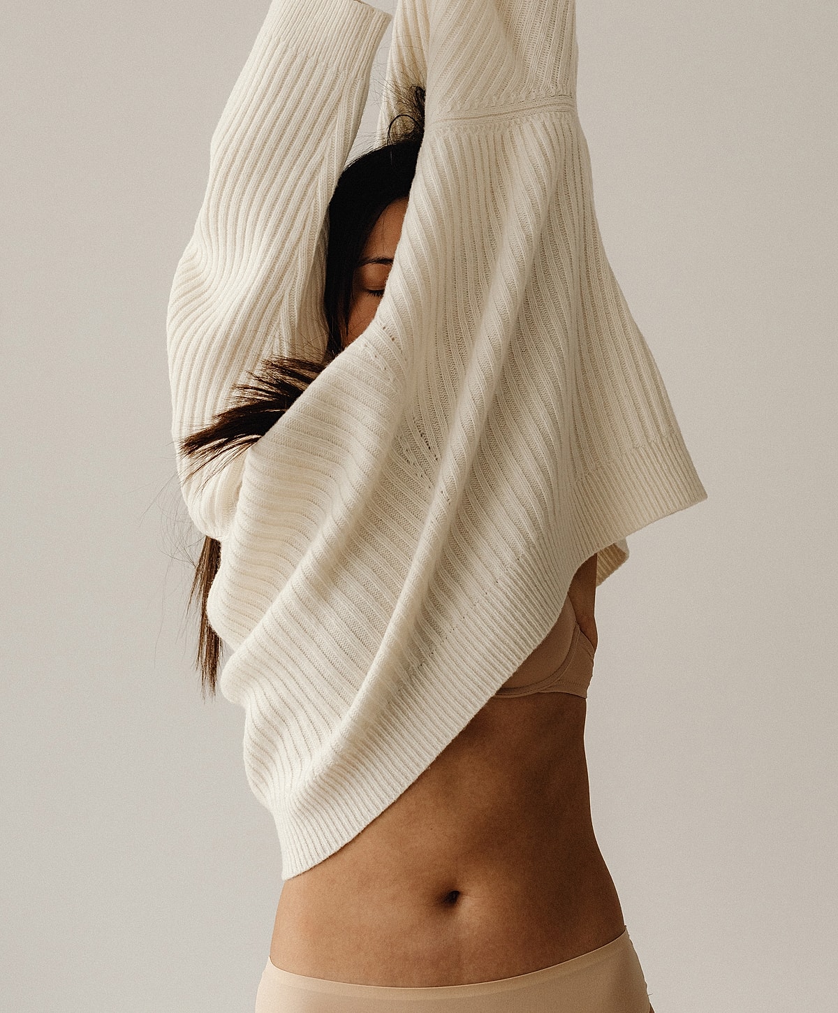 Smiling woman in casual attire against textured wall.