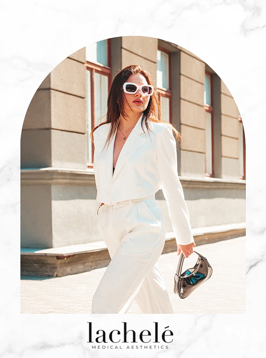 Woman in white suit walking outdoors fashionably.