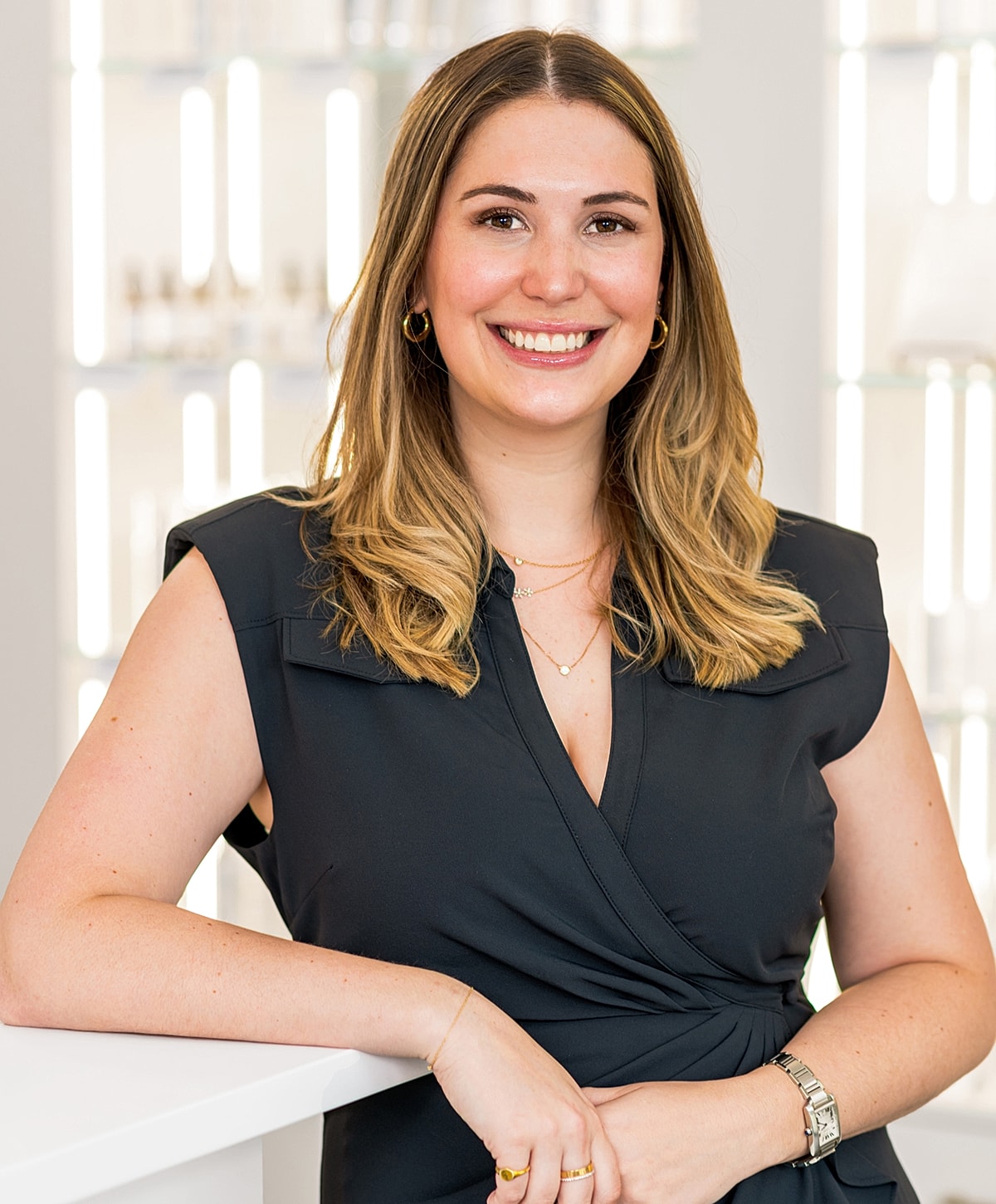 Smiling woman in black suit, skincare background.