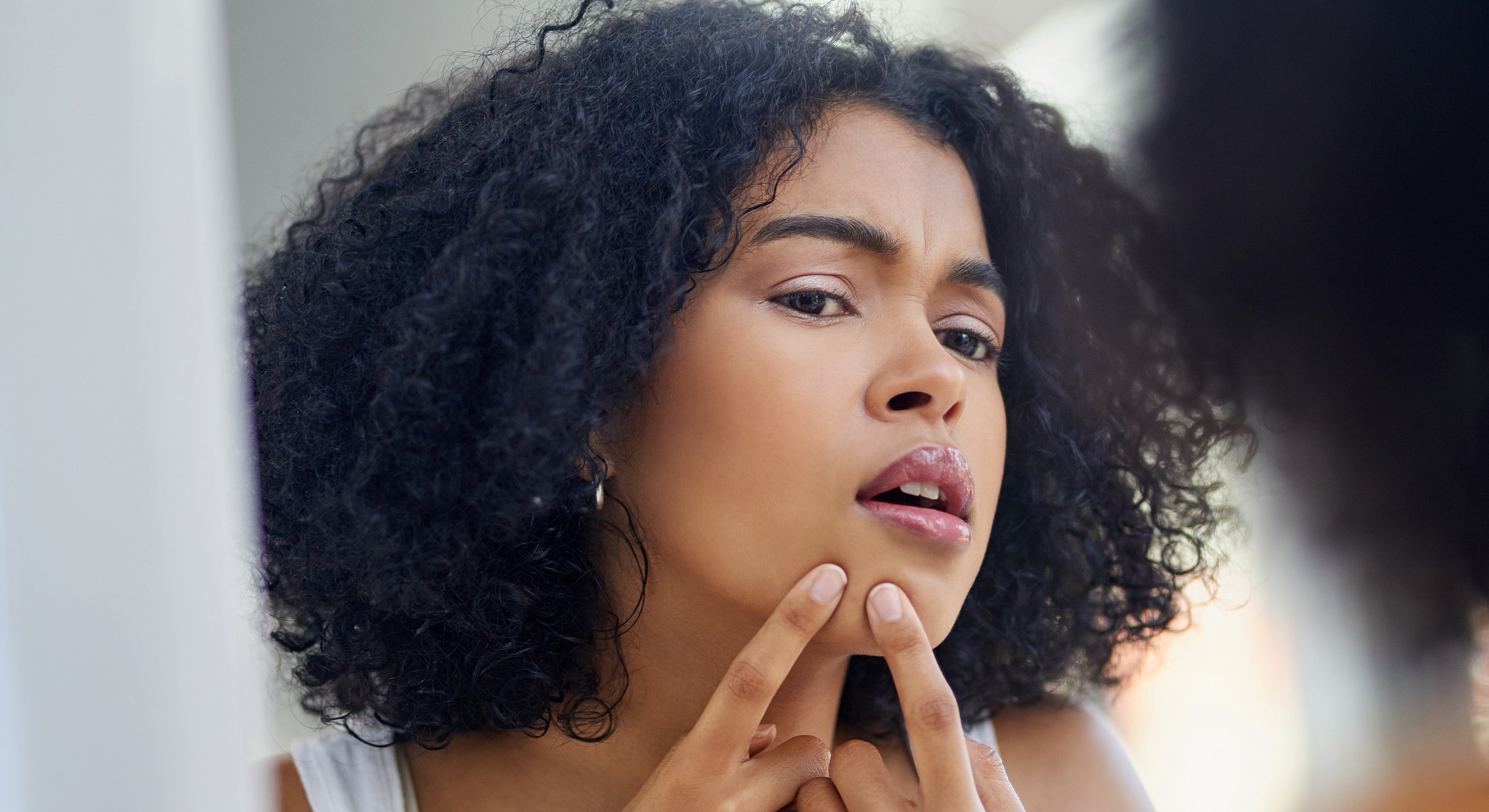 Woman examining her skin in mirror.