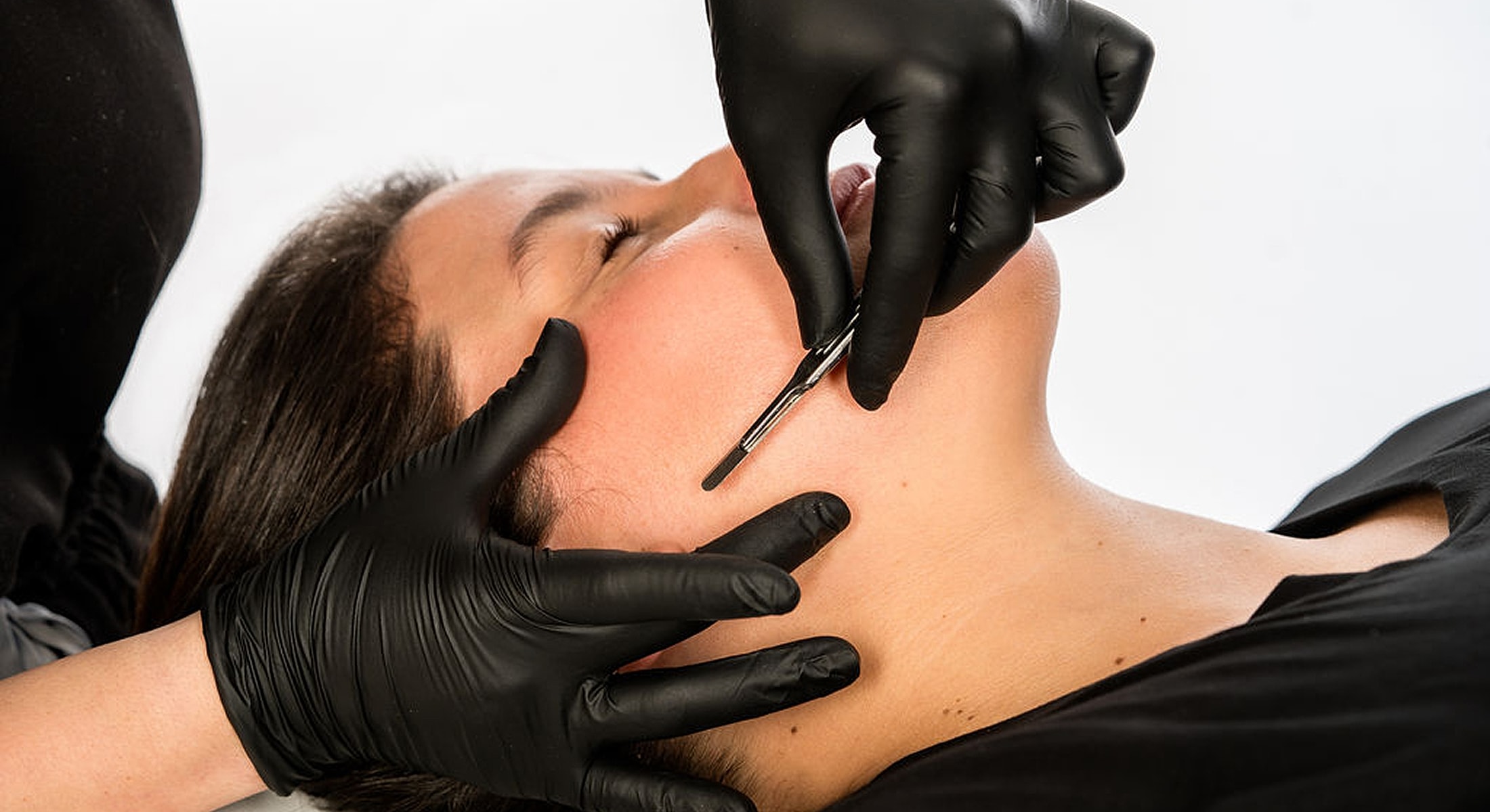 Facial treatment in progress with gloved hands.