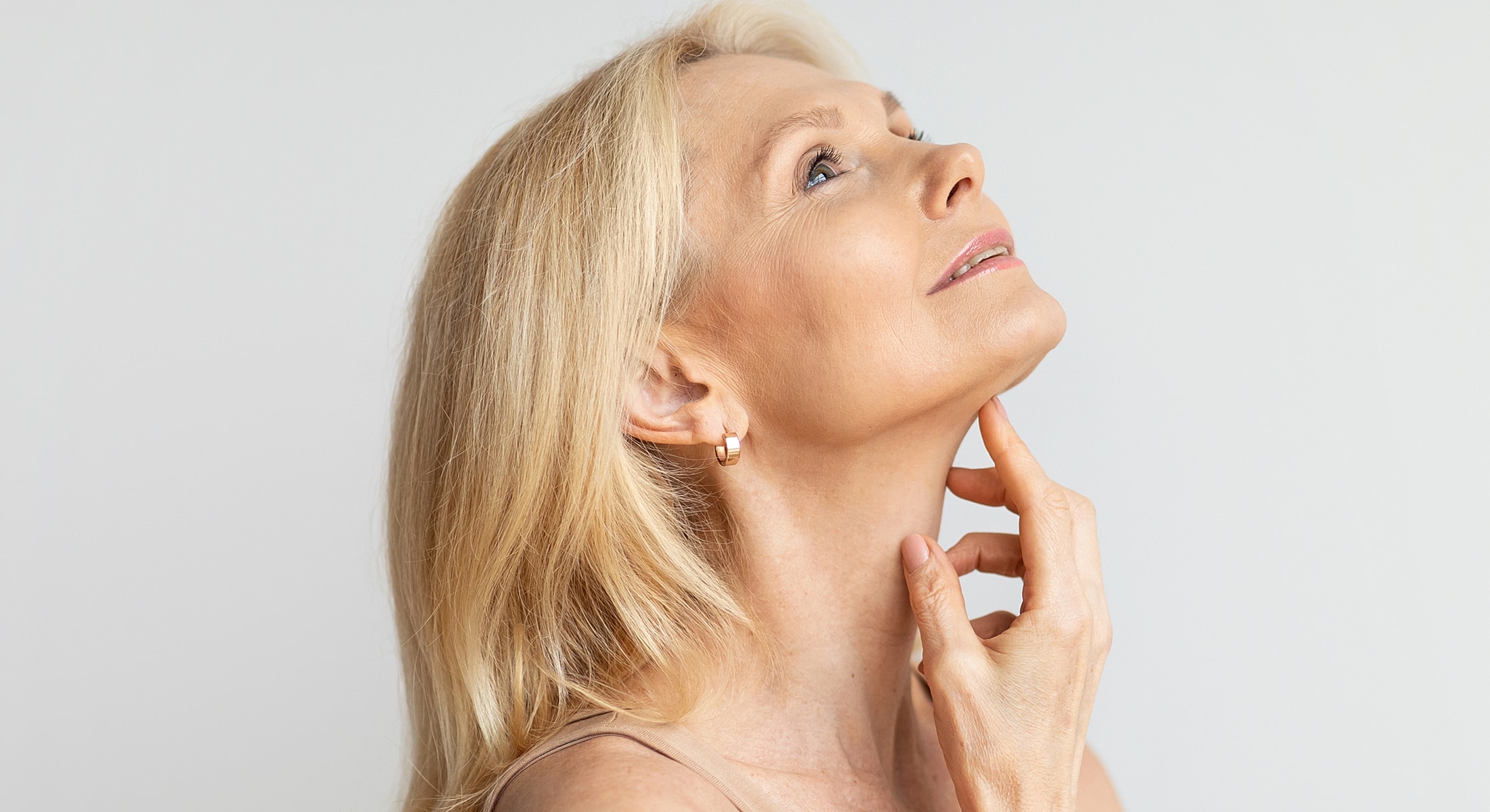 Woman looking up thoughtfully with hand on chin.