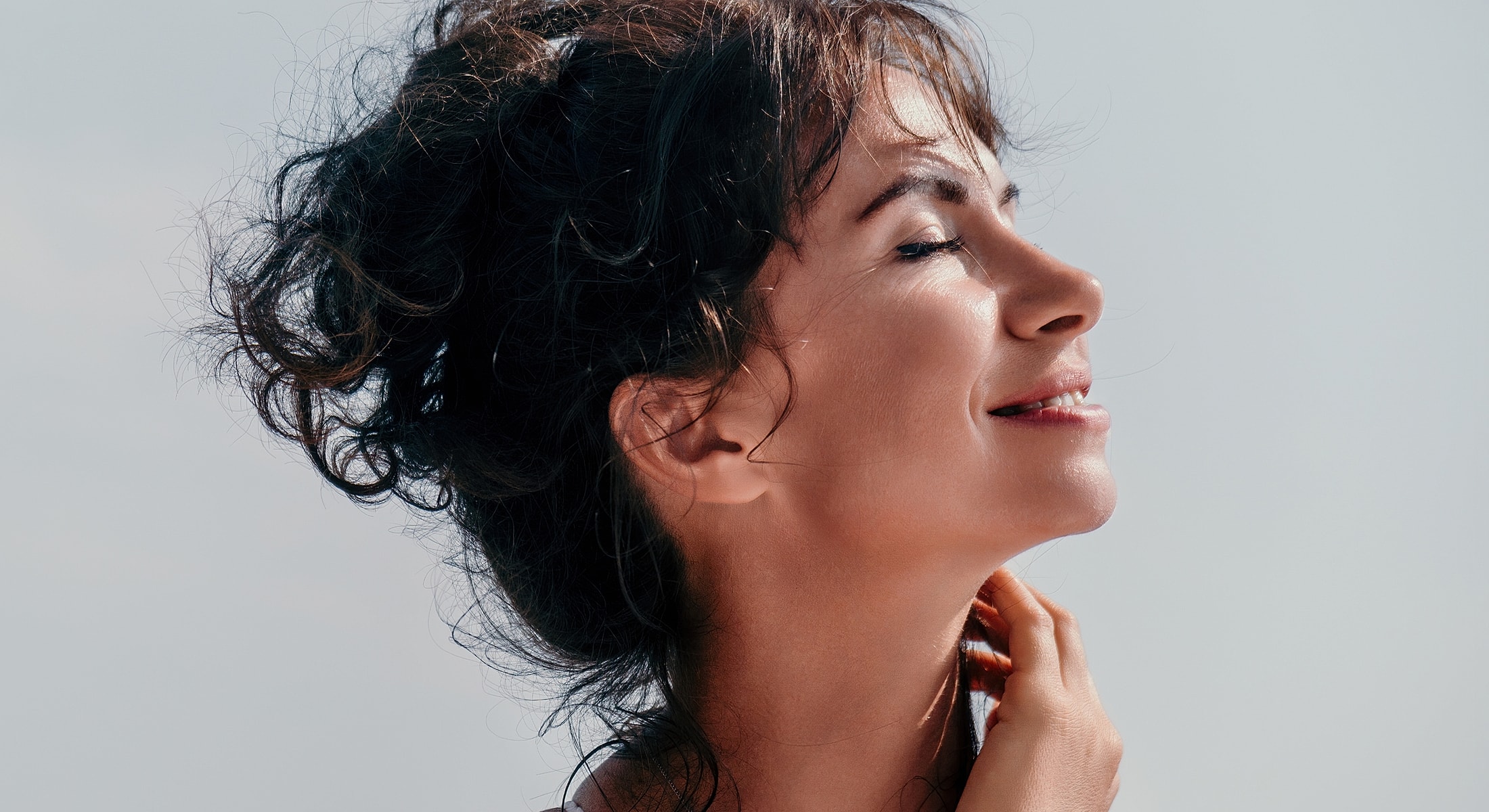 Woman enjoying sunlight with a serene expression.