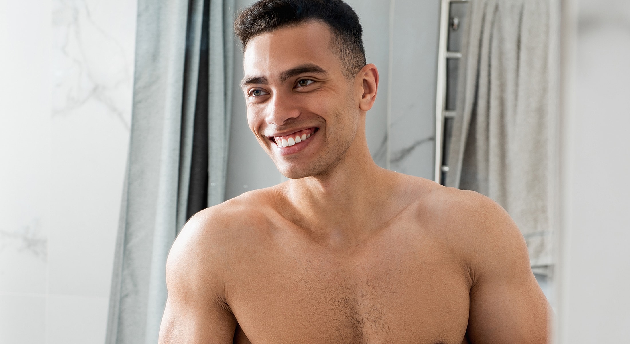 Smiling man in a bathroom, shirtless.