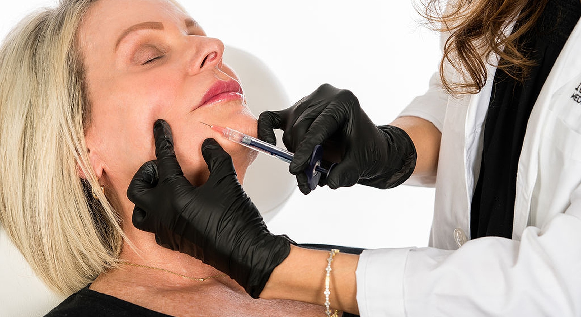 Injecting dermal filler in client's face.