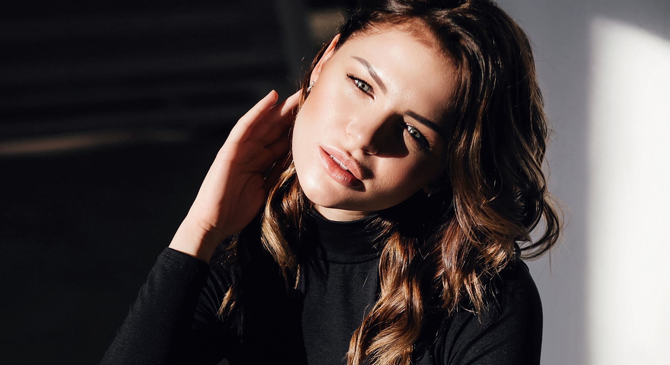 Young woman with wavy hair in soft lighting.