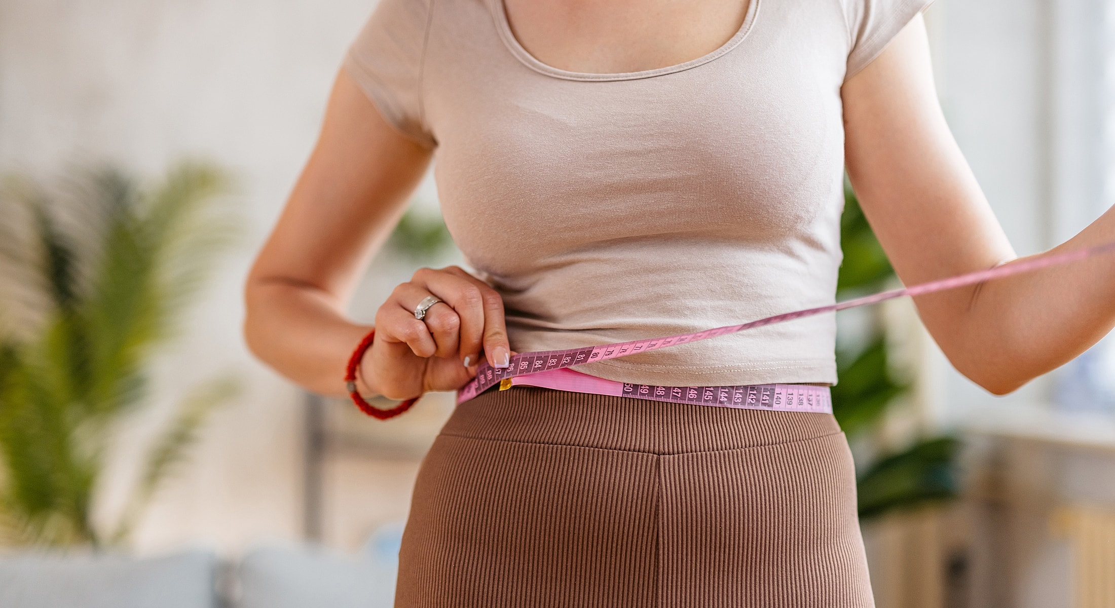 Woman measuring her waist with a tape measure.